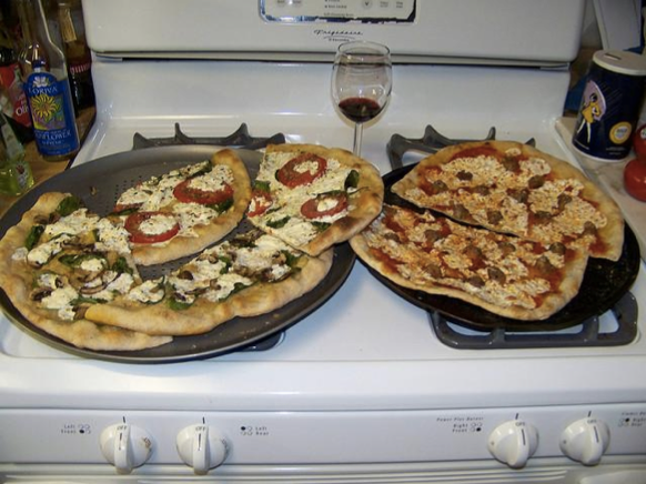 Descrição gerada por computador: “Two pizzas sitting on top of a stove top oven”